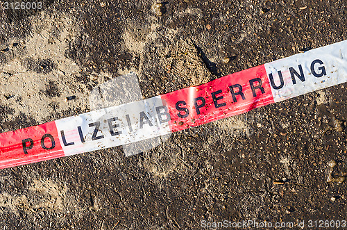 Image of German police line red white tape on street asphalt dirt