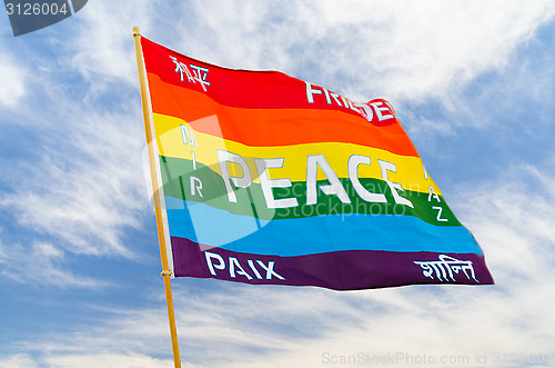 Image of Rainbow multiolored peace flag wind flying against blue sky