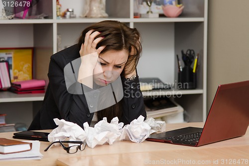 Image of The girl at a computer with bunch crumpled sheets of paper