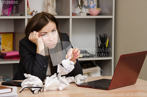 Image of Sad girl in the office with a bunch of crumpled paper