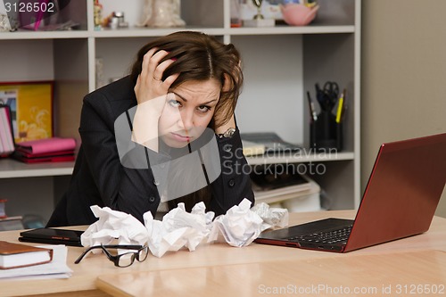 Image of The girl at the computer holding head in his hands