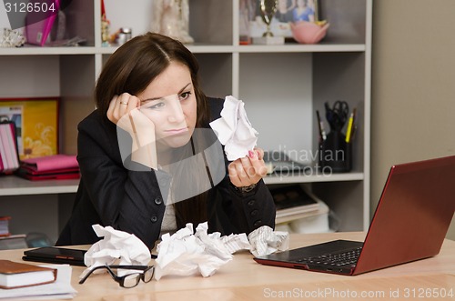 Image of Sad girl in the office holds a crumpled sheet of paper