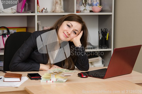 Image of Pretty teenage girl in the office with a bundle of banknotes