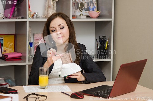 Image of Girl in the office broke off a piece of chocolate