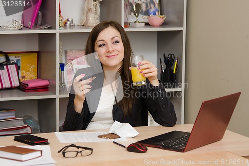 Image of Girl in the office holding a glass of juice and chocolate