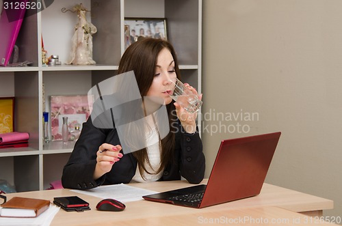 Image of Business woman at the desk drinking water