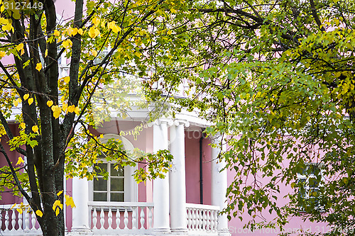 Image of White balcony of pink house of classic style in autumn garden 