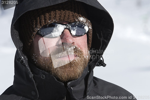 Image of Young man with snow in his face looks into the distance 