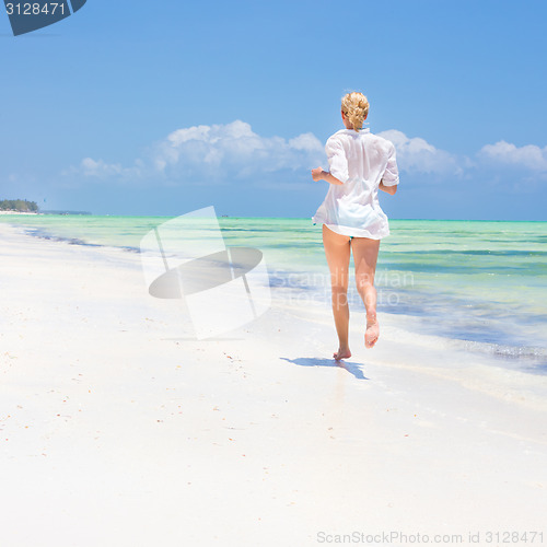 Image of Woman running on the beach in white shirt. 