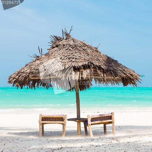 Image of Two deck chairs and umbrella on tropical beach.