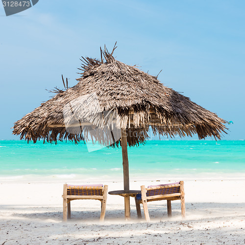 Image of Two deck chairs and umbrella on tropical beach.