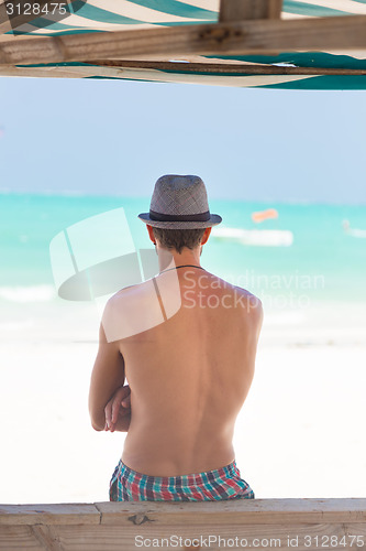 Image of Hipster man with hat on tropical sandy beach.