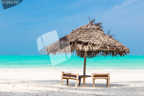 Image of Two deck chairs and umbrella on tropical beach.