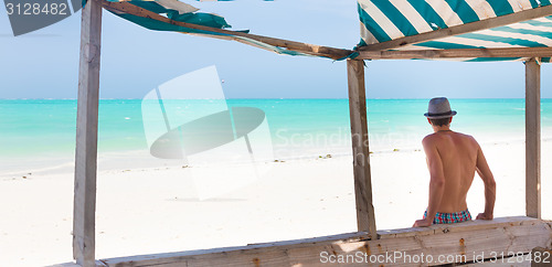 Image of Hipster man with hat on tropical sandy beach.