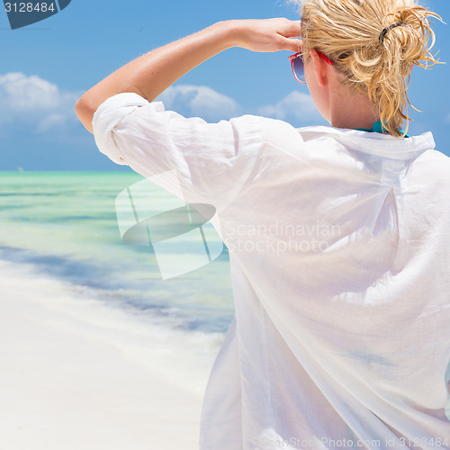 Image of Woman on the beach in white shirt. 