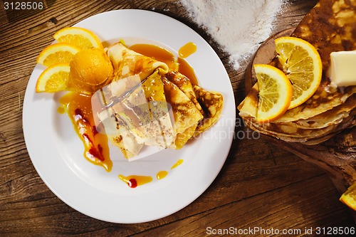 Image of stuffed pancakes with orange syrup and ice-cream