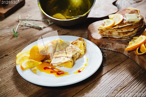 Image of stuffed pancakes with orange syrup and ice-cream