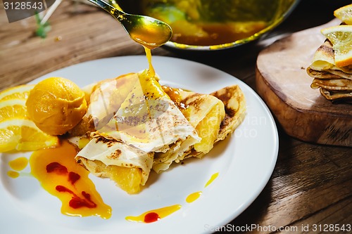 Image of stuffed pancakes with orange syrup and ice-cream