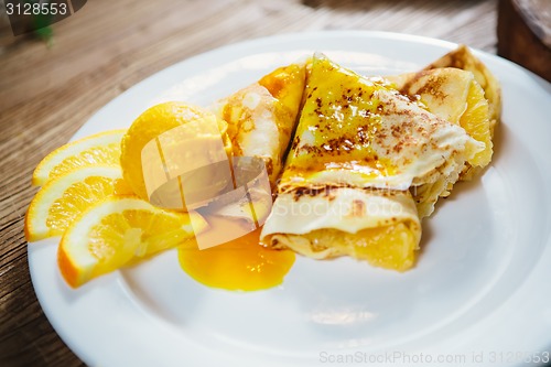 Image of stuffed pancakes with orange syrup and ice-cream