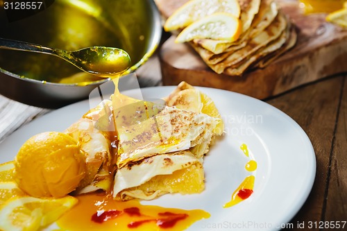 Image of stuffed pancakes with orange syrup and ice-cream
