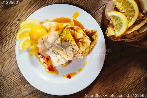 Image of stuffed pancakes with orange syrup and ice-cream