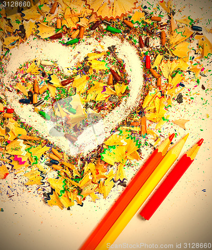 Image of heart, three pencils and varicolored wooden shavings