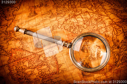 Image of Vintage magnifying glass lies on an ancient world map