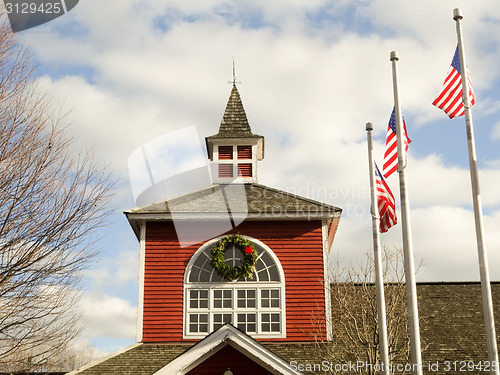 Image of red white and blue flags on a pole with american architecture