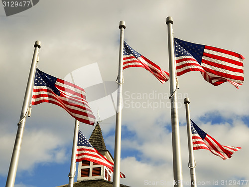 Image of red white and blue flags on a pole with american architecture