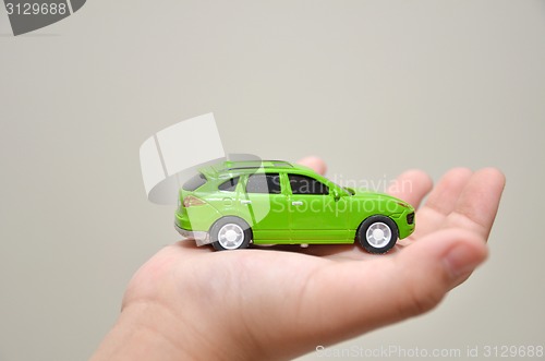 Image of Green toy car on a right hand