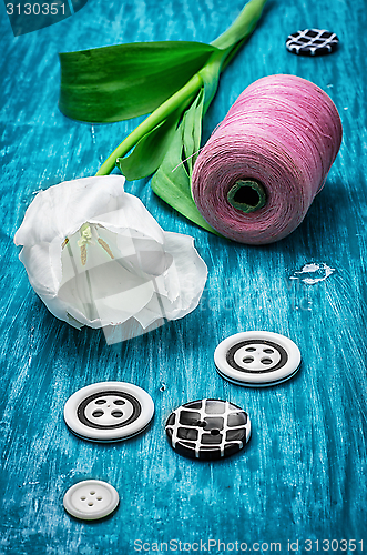 Image of one white tulip and buttons with threads