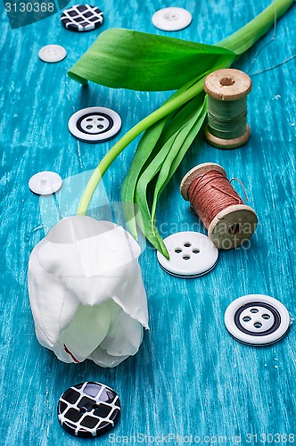 Image of one white tulip and buttons with threads