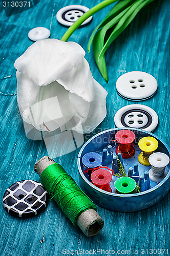 Image of one white tulip and buttons with threads