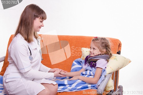 Image of Pediatrician looks at the sick child and keeps his hand