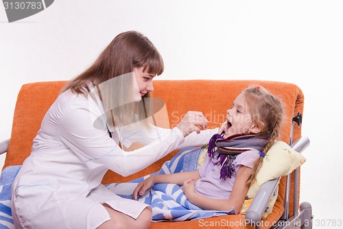 Image of Pediatrician looks at the throat of a sick child