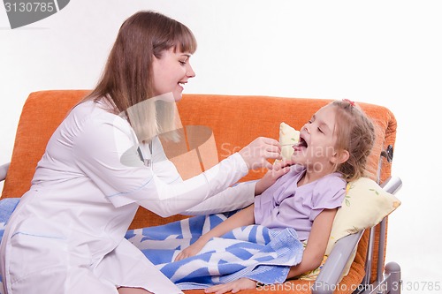 Image of The doctor examines the throat Sick little girl in bed