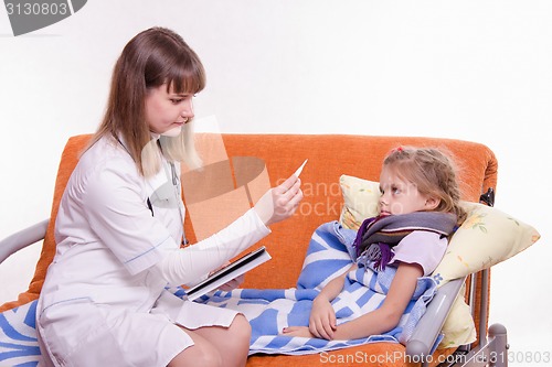 Image of Pediatrician about sick girl looking at a thermometer