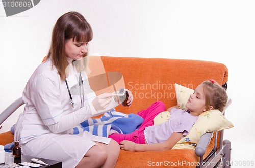 Image of The doctor pours a spoonful of medicine to give sick child