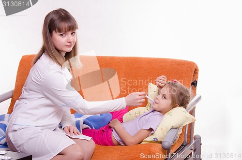 Image of The doctor in a white coat measures temperature at sick girl