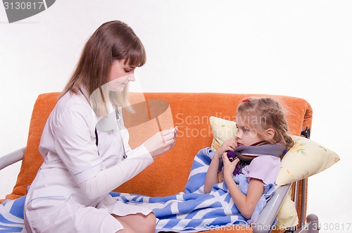 Image of Doctor near sick girl looking at a thermometer