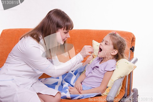 Image of The doctor looks at the throat of a sick child