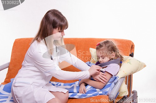 Image of The doctor puts a thermometer sick child