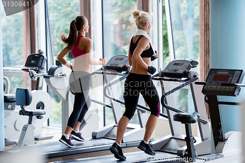Image of friends  exercising on a treadmill at the bright modern gym
