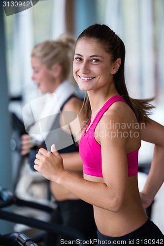 Image of friends  exercising on a treadmill at the bright modern gym