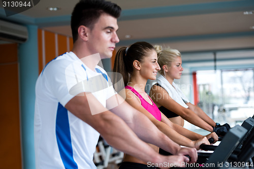 Image of friends  exercising on a treadmill at the bright modern gym