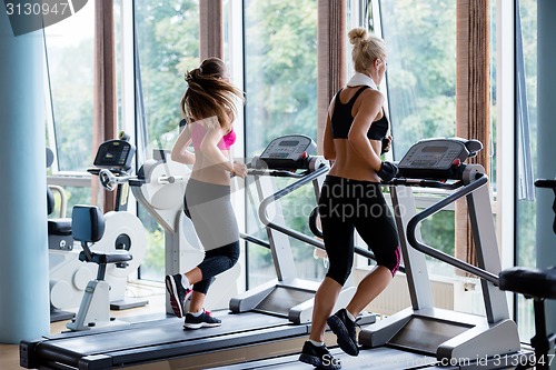 Image of friends  exercising on a treadmill at the bright modern gym