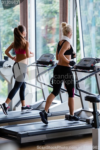 Image of friends  exercising on a treadmill at the bright modern gym