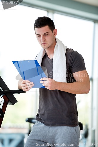 Image of trainer with clipboard standing in a bright gym