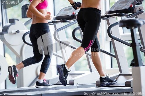 Image of friends  exercising on a treadmill at the bright modern gym