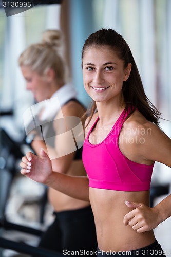 Image of friends  exercising on a treadmill at the bright modern gym
